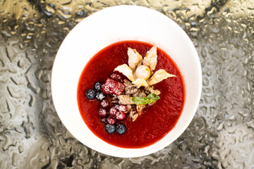 Top view on strawberry soup with fresh berry in white plate on t