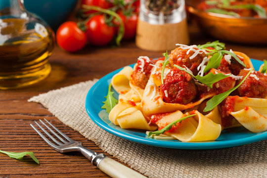 Italian pasta pappardelle with meatballs in tomato sauce.