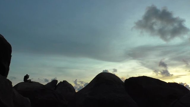 silhouette of a man sitting on a rock and takes pictures