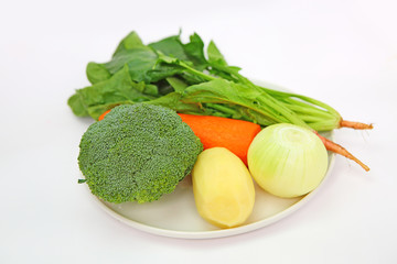 Fresh vegetable in white plate (onion, carrot, broccoli, potato and spinach)