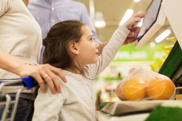 family weighing oranges on scale at grocery store