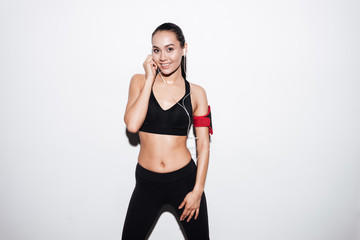 Happy fitness woman with armband standing and listening to music