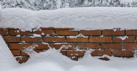 Red brick wall covered with snow