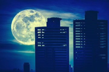 Silhouettes of two skyscrapers construction with background of full moon