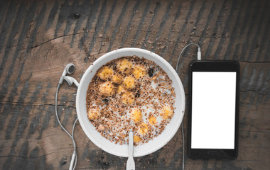 Breakfast, smartphone with white screen and headphones. Muesli