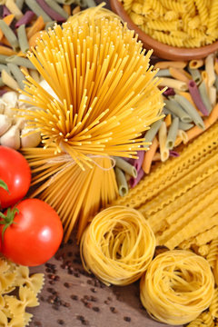 Uncooked Italian pasta, ripe tomatoes branch and black pepper