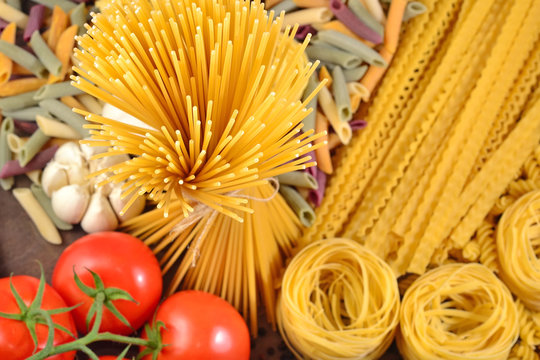 Uncooked Italian pasta, ripe tomatoes branch and garlic