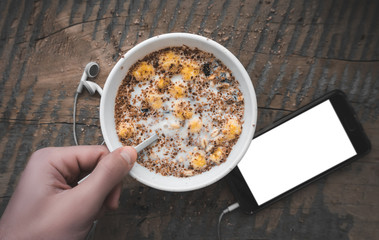 Breakfast, smartphone with white screen and headphones. Muesli