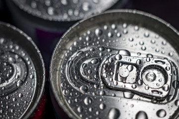 Top of aluminum cans of soda pop covered in droplets of water