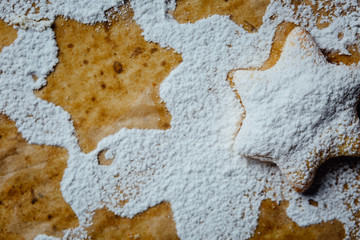 Cookie on a baking pan covered with powdered sugar.