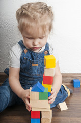 Little cute girl playing with a wooden constructor