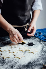 Hands of cook putting cookies to the flour. Vertical studio shot. 