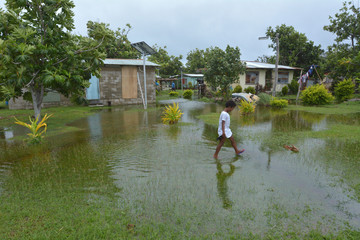 Fijian girl walks over flooded land in Fiji
