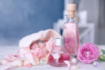 Obraz na płótnie Canvas Essential oils and rose petals on wooden table