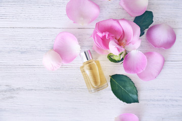 Essential oil with flower petals on wooden background