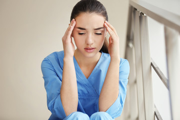 Depressed medical worker sitting on stairs in clinic