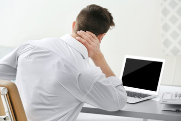 Man suffering from neck pain in office