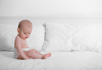 Cute funny baby sitting on bed at home