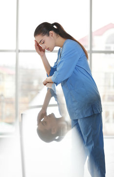 Depressed medical worker standing near banisters in clinic