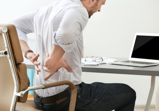 Young Man Suffering From Backache In Office, Closeup