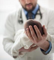 Pediatrician holding a newborn baby boy in hospital