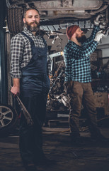 Fototapeta na wymiar Two bearded men repairing car in a garage.