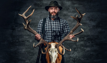 Portrait of hunter man holds a deer's skull.