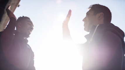 Two friends about to high five in the sunlight, teamwork concept