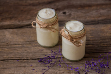 Yogurt in jar on the wooden table with purple dried plant