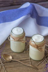 yogurt in jars on the wooden table with napkin, spoon and dried