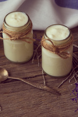 yogurt in jars on the wooden table with napkin, spoon and dried
