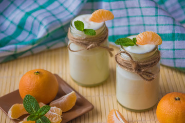 Fresh organig natural white yogurt in glass jars with tangerine