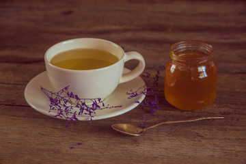 Cup of tea with honey in jar on the wooden table