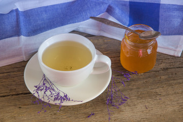Green tea in a white cup and jar of honey with spoon and blue ki