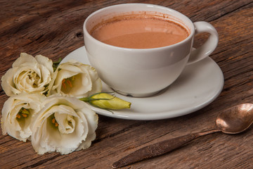 Still life with cup of coffee and flowers Eustoma on wooden back