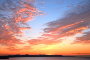 Naklejka na ściany i meble 青空に紅に染まる日の出時の雲 江の島の日の出の空が美しい。