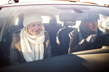 Senior couple in winter clothes driving a car