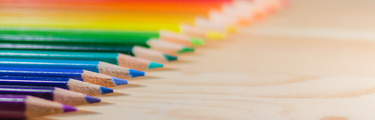 Obraz premium Row of colorful pencils rainbow order on wooden table