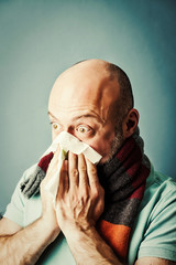 middle-aged bearded man blowing his nose into a napkin, colds, r