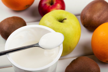 spoon with yogurt and fruits on white wooden table