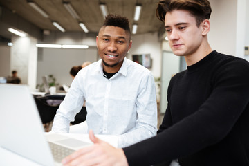 Two students sitting in library and using laptop computer.
