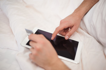 Young man holding credit card and using tablet. Online shopping concept.