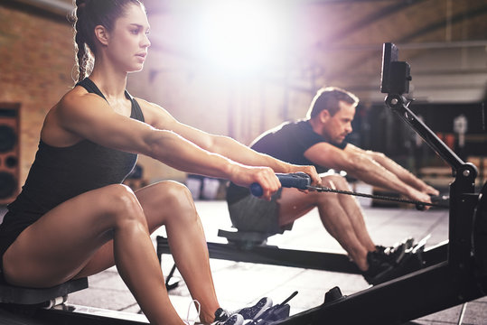 People having hard workout on rowing machines