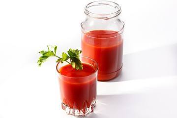 Tomato juice is poured from the glass jar into a glass.