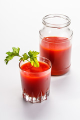 Tomato juice is poured from the glass jar into a glass.