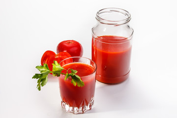Tomato juice is poured from the glass jar into a glass.