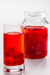 Fototapeta na wymiar Cherry compote in a jar in a glass on a white background.