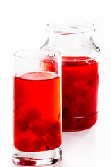 Cherry compote in a jar in a glass on a white background.