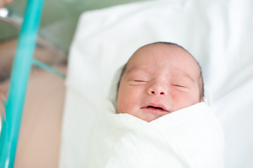 Newborn baby in hospital with id ribbon on his hand