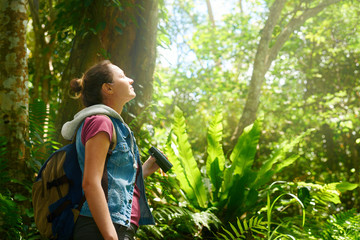 Female traveller watching through binoculars wild birds in the jungle.